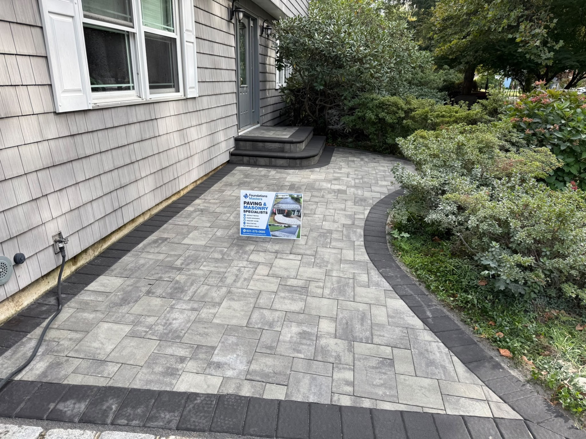 Finished gray paver walkway with curved charcoal border on Long Island